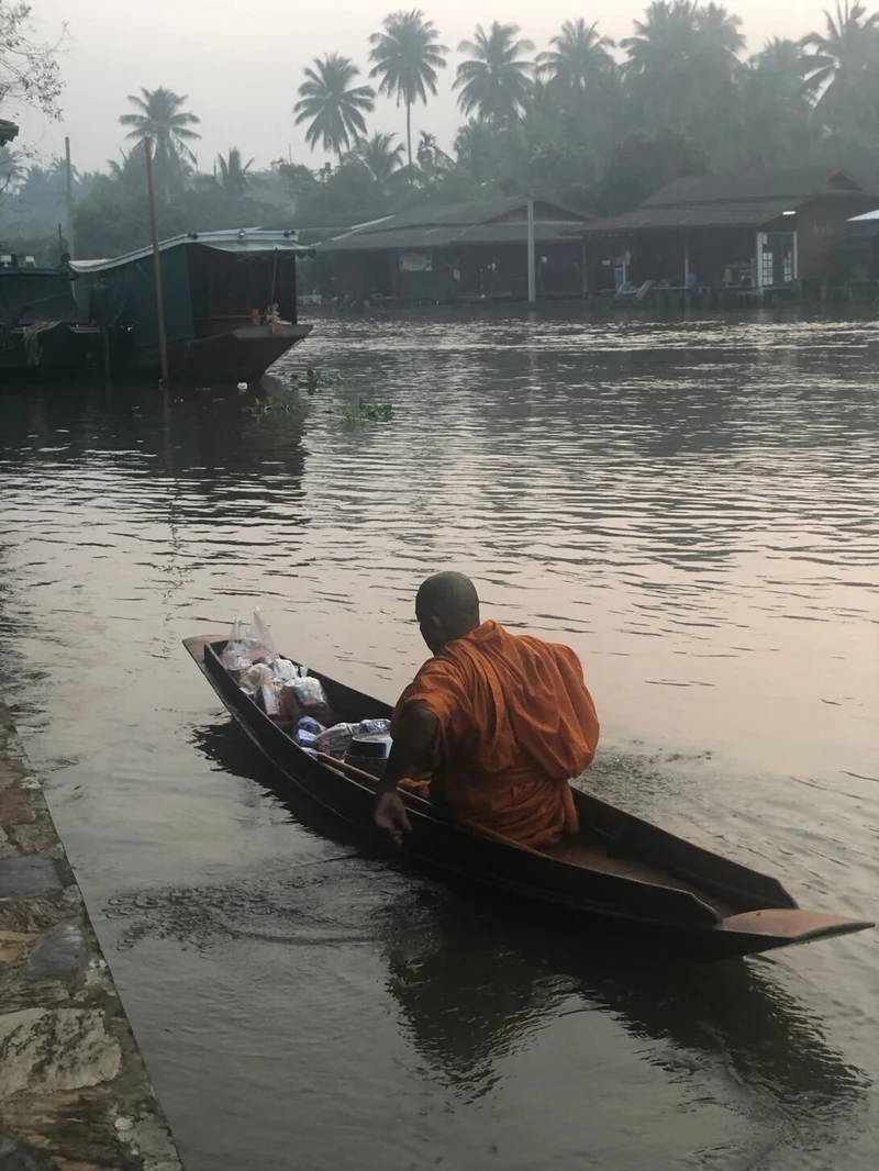 タイの早朝の川辺で小船を進める人